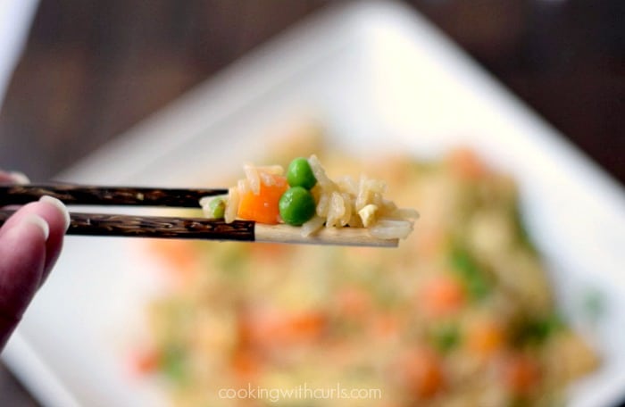Close up image of fried rice, carrots and peas on wooden chopsticks