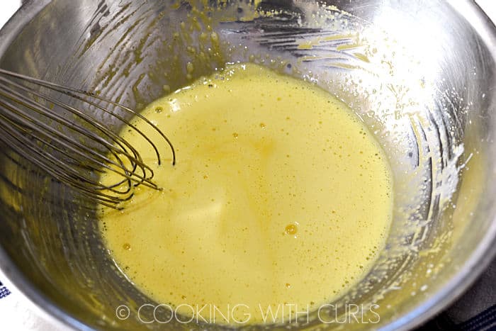 Egg mixture tempered with hot cream in a stainless steel bowl. 