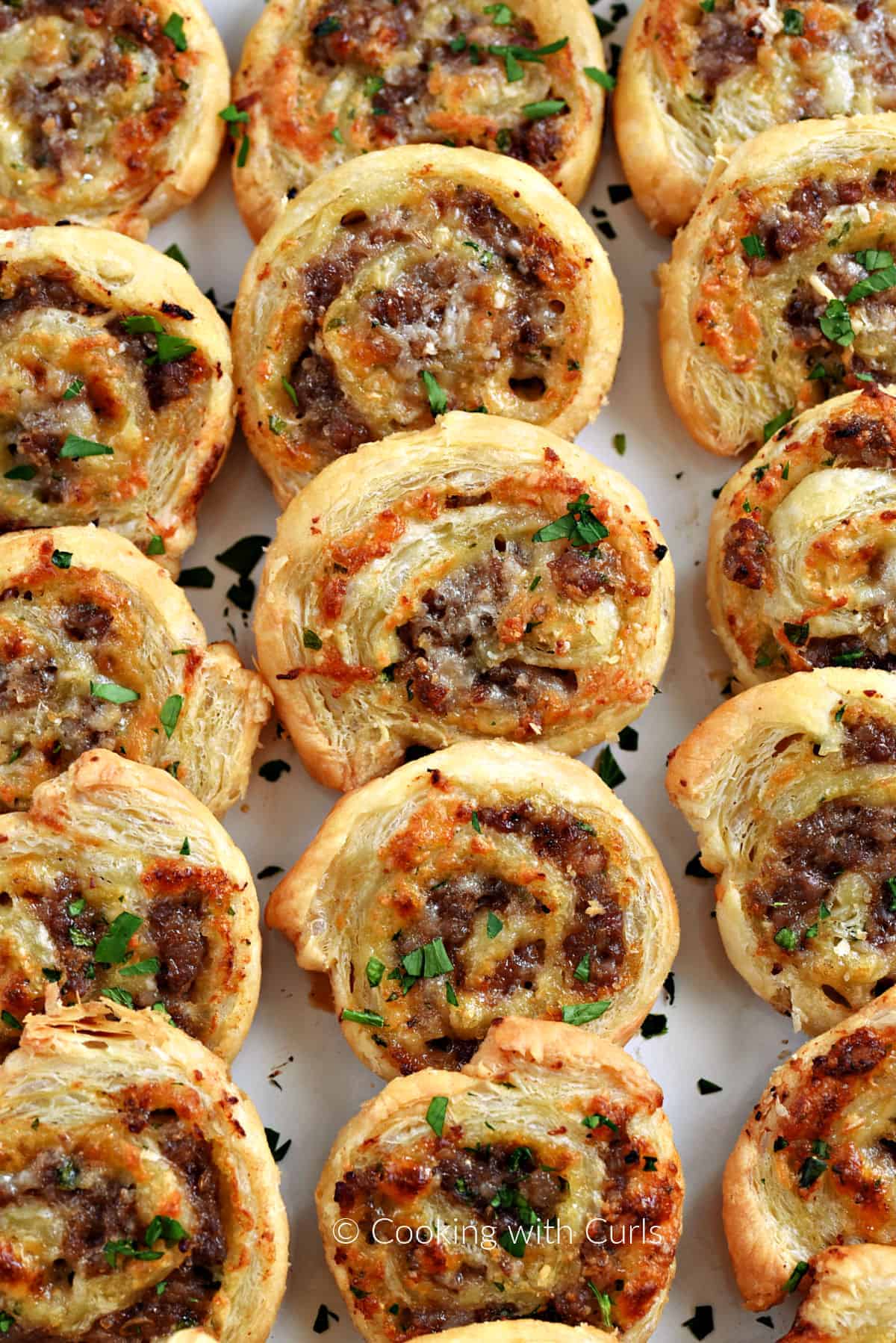 Fifteen Sausage Pinwheels lined up on a platter. 