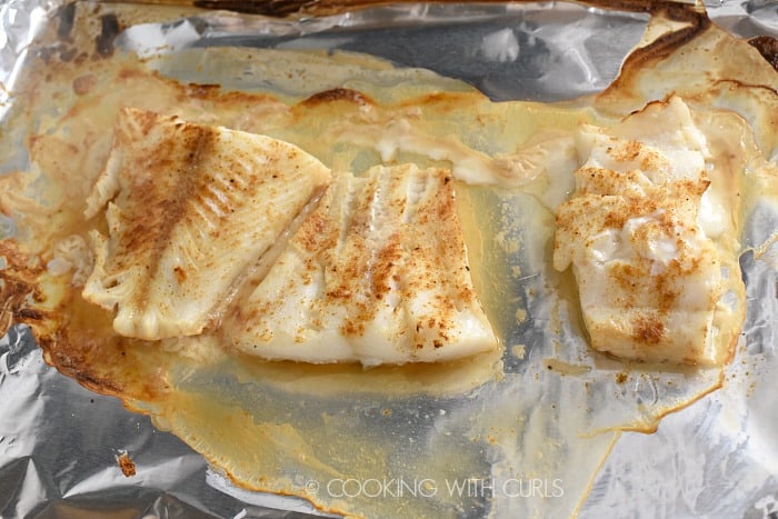 Three seasoned cod filets cooked on a baking sheet.