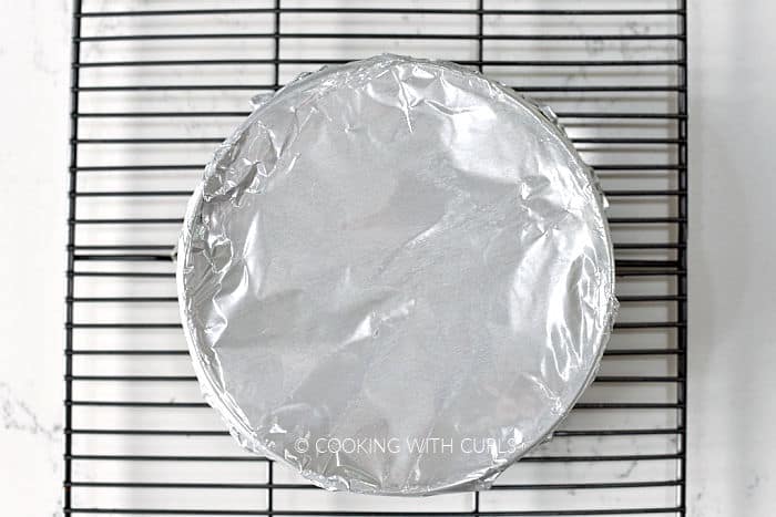 Foil wrapped springform pan on a wire cooking rack. 