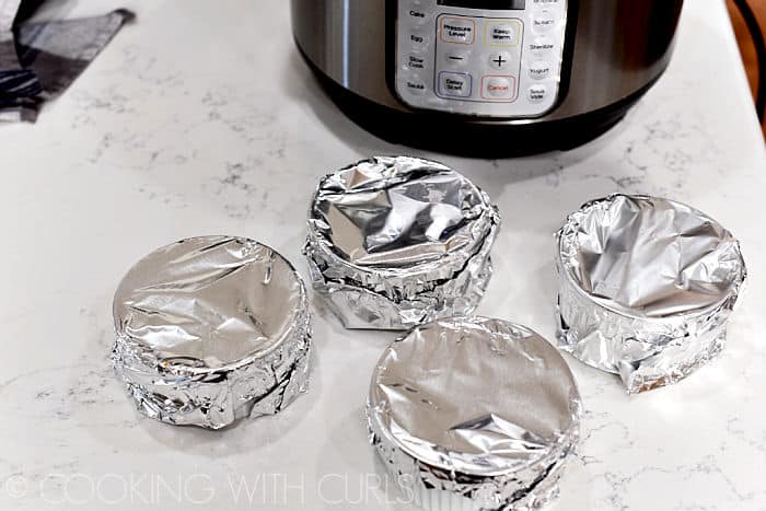 Four ramekins topped with foil. 