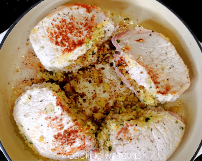 Four stuffed pork chops in a skillet. 