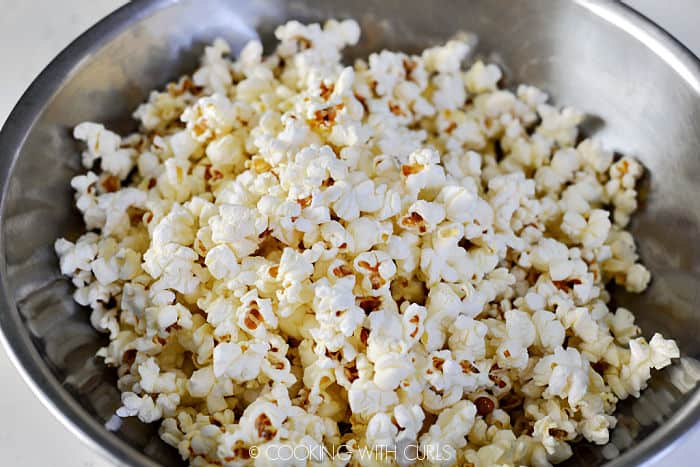 Freshly popped popcorn in a stainless steel bowl. 