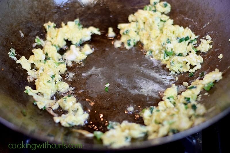 Scrambled eggs pushed up the sides of a wok.