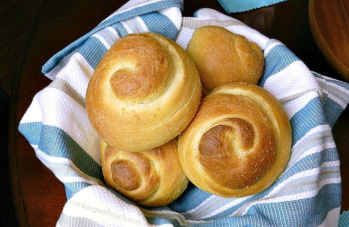 garlic dinner rolls in a basket lined with a blue and white striped napkin