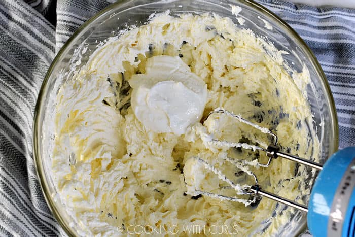 Greek yogurt added to the beaten cream cheese and sugar mixture in a large glass bowl. 