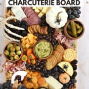 Halloween themed charcuterie board with meats, cheeses, crackers, and fruits with title graphic across the top.