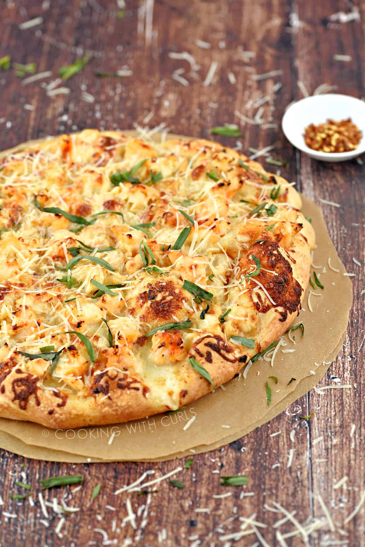 Homemade Lobster Pizza on parchment paper circles topped with fresh tarragon leaves and grated Parmesan. 