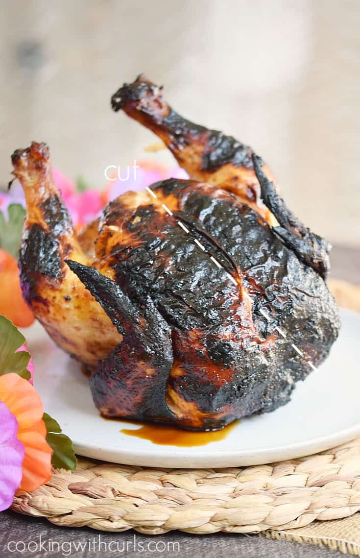 Whole Huli Huli Chicken on a white plate with a line to show where to cut.