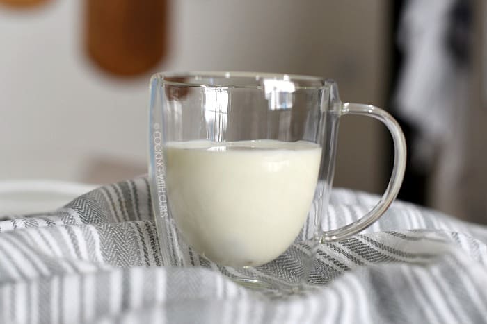 Ice cubes and milk in a clear glass coffee mug.