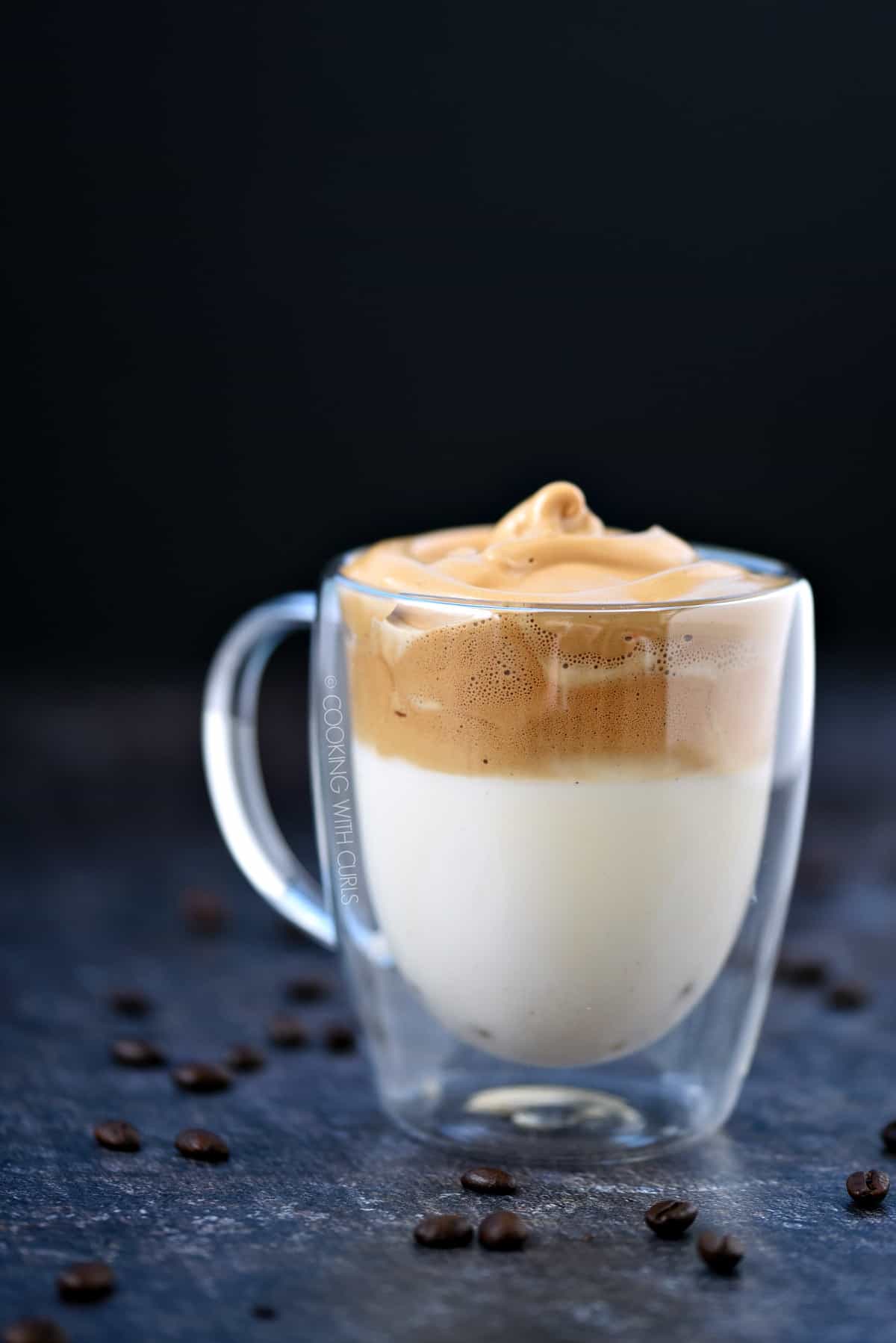 A layer of milk topped with a layer of Whipped Dalgona Coffee in a clear glass mug.