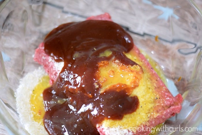 Ground beef, panko crumbs, egg and barbecue sauce in a glass bowl.