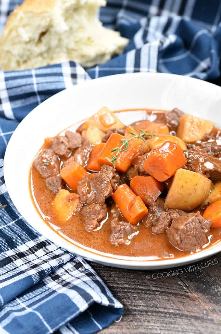 Instant Pot Beef Stew with large chunks of beef, carrots and potatoes in a white bowl.