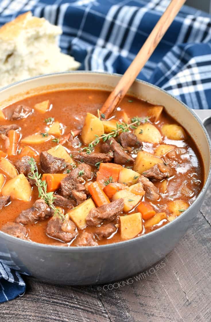 Beef Stew in a large, gray Dutch oven with a wooden spoon.