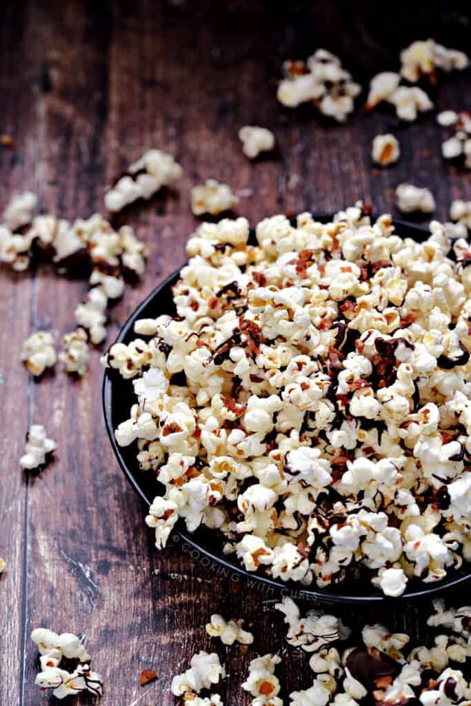 Instant Pot Chocolate and Bacon Popcorn overflowing a dark blue bowl onto a wooden surface.