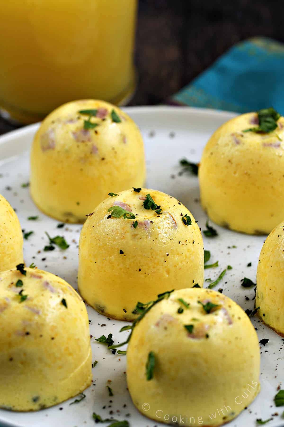 Seven Instant Pot Denver Omelet Egg Bites on a plate topped with chopped parsley.