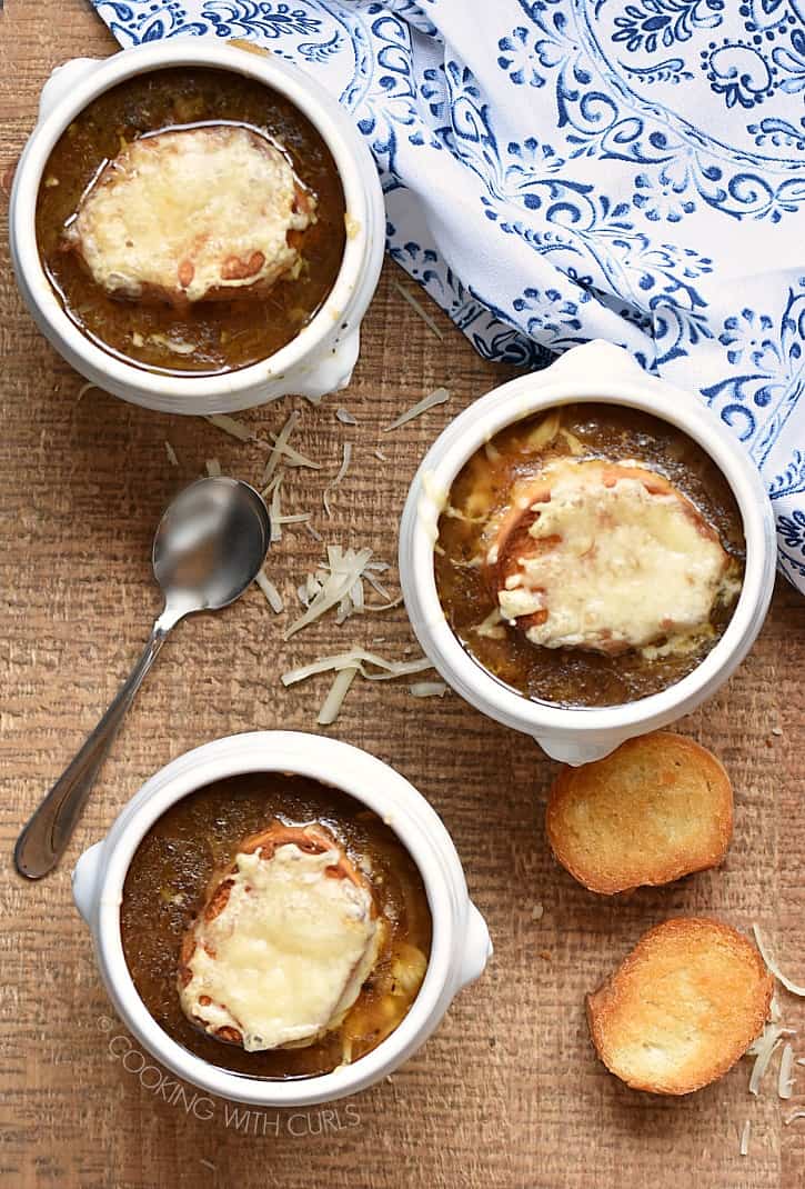 Three bowls of French Onion Soup topped with melted cheese bread.