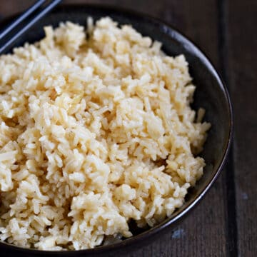 Garlic Rice in a blue bowl with blue chopsticks on the edge.