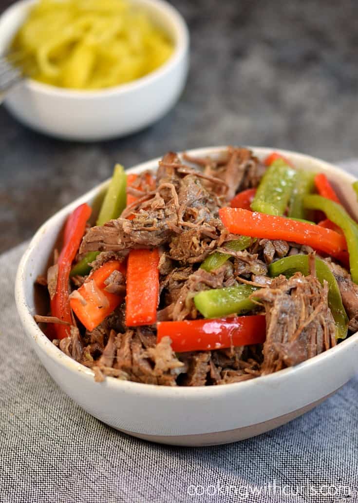 Instant Pot Italian Beef shredded beef with sautéed green and red bell pepper slices in a white bowl.