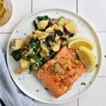 A salmon filet and mashed potatoes mixed with spinach on a white plate with two lemon wedges with title graphic across the top.