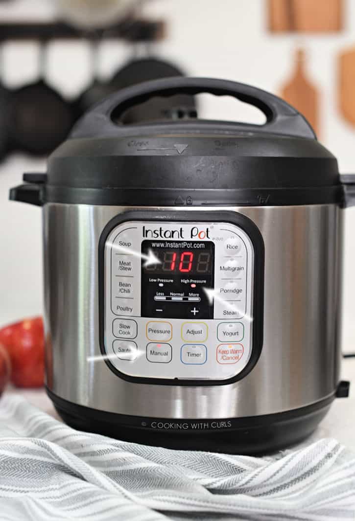 instant pot set for 10 minutes on manual high pressure with arrows pointing to each illuminated button. 