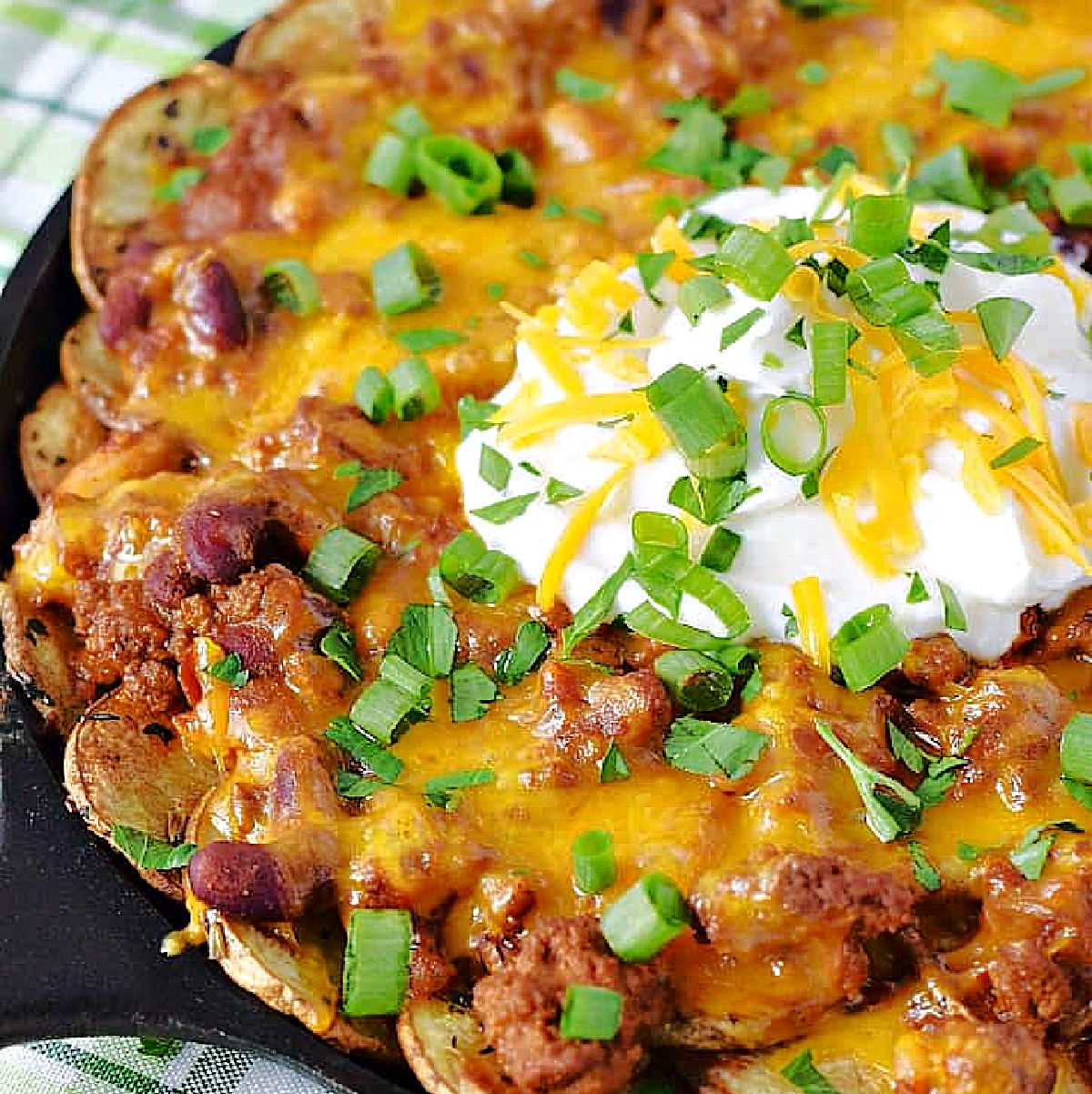 Thin sliced potato slices topped with chili, melted cheese, sour cream and green onions.