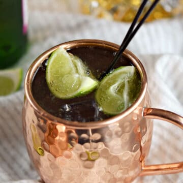 Irish Mule in a copper mug with lime wedges and bottle of whiskey and ginger beer in the background.