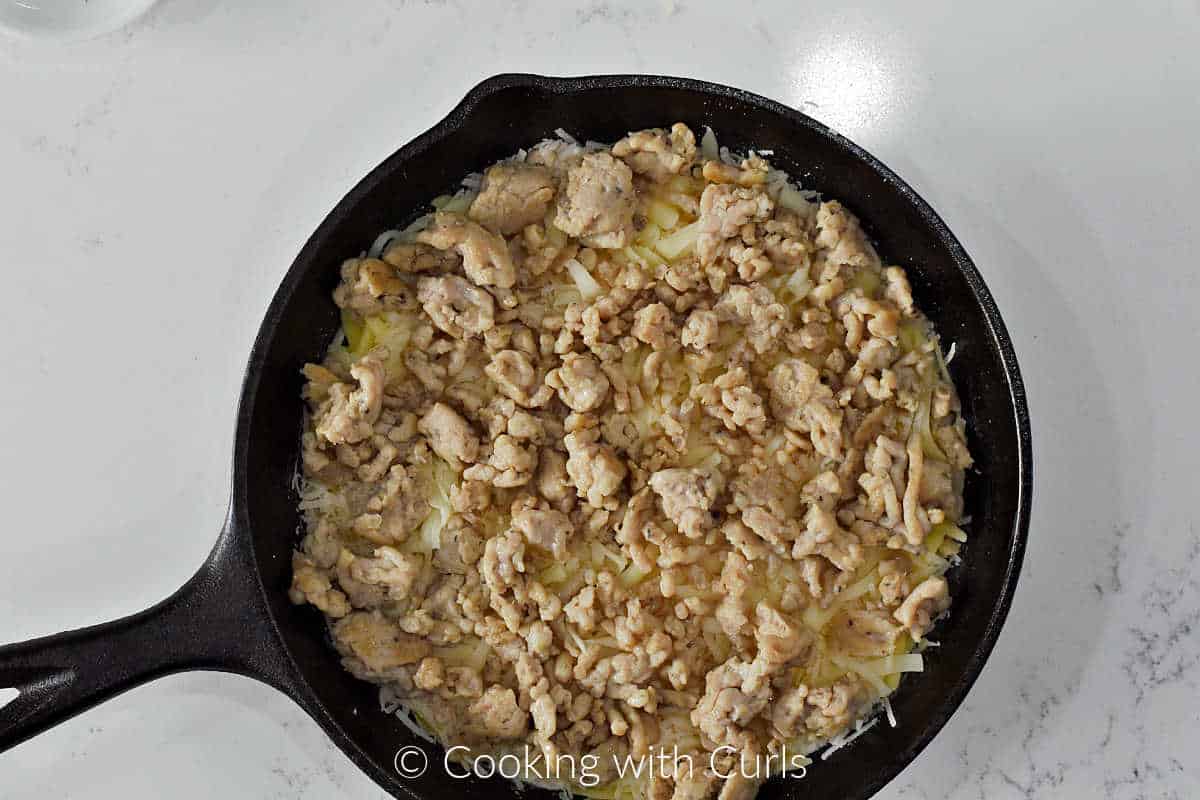 Italian-sausage-on-top-of-cheese-in-a-cast-iron-skillet.