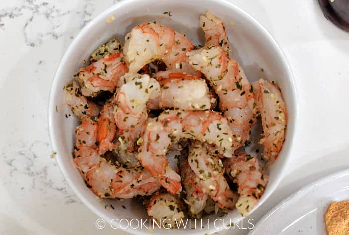 Large shrimp tossed with Greek seasoning in a small bowl. 