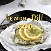 A cod filet topped with dill and a lemon slice in parchment paper sitting on a black plate with title graphic across the top.