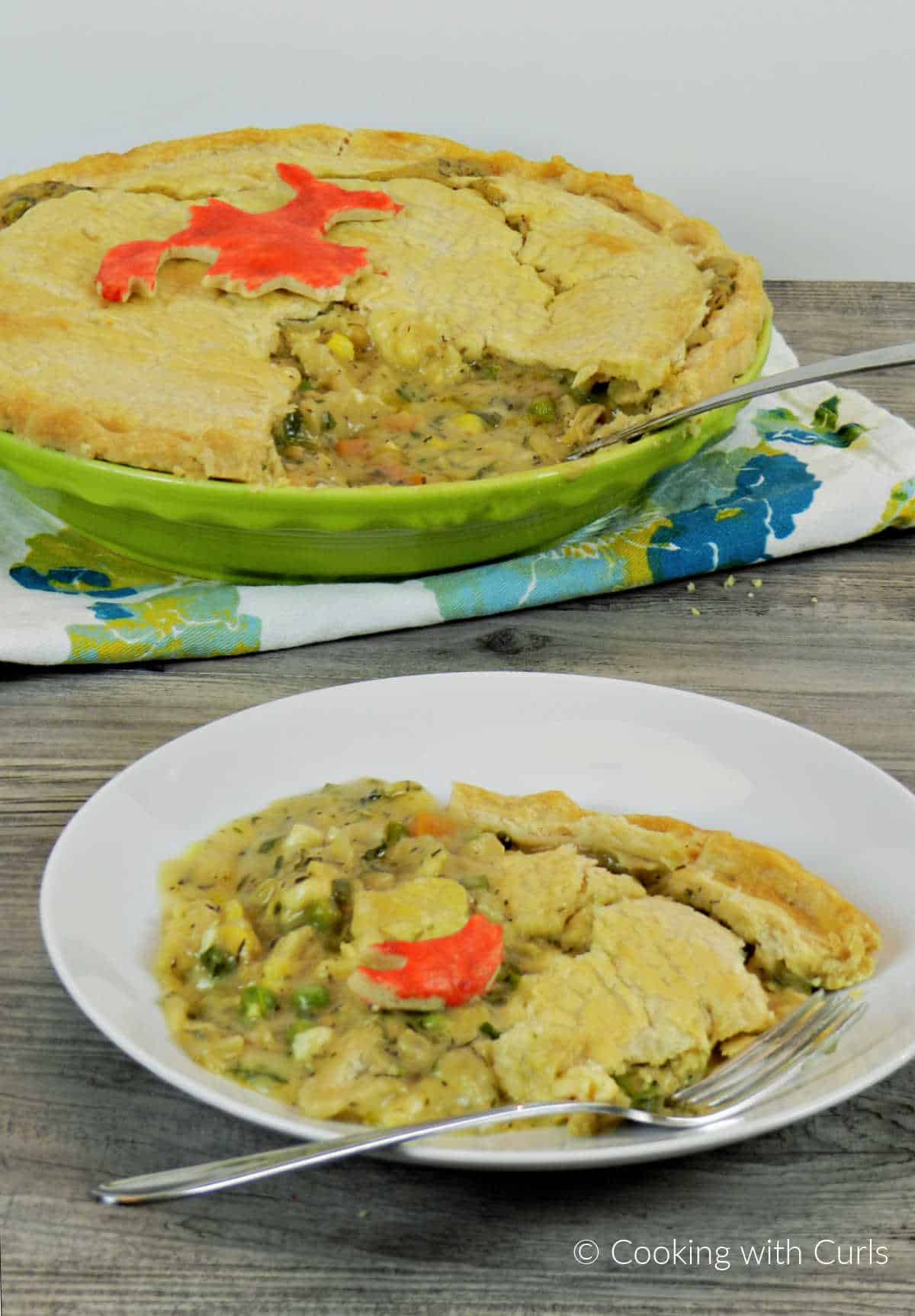 Lobster Pot Pie with flaky crust and rich filling in a white bowl sitting in front of the pie dish.