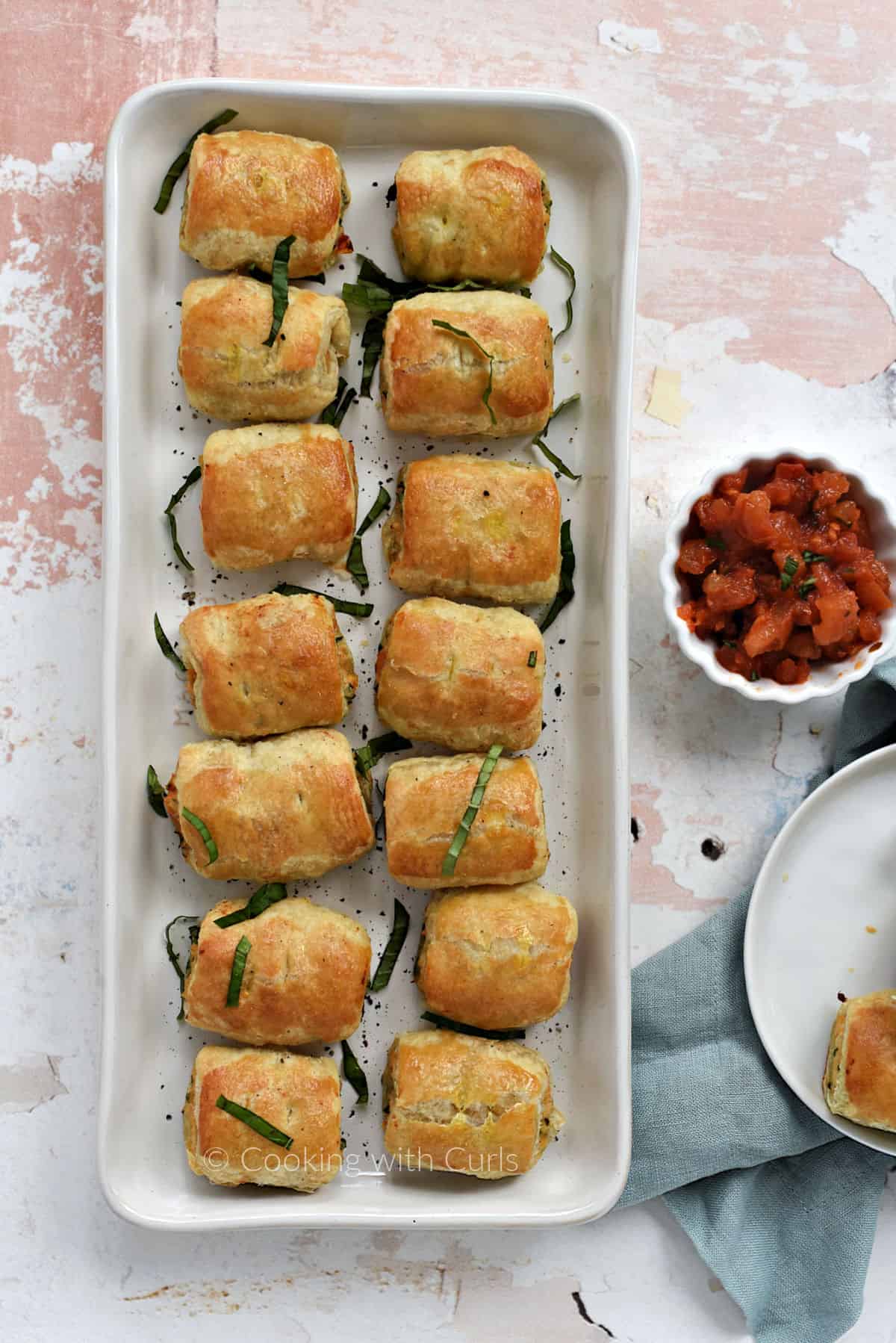 Looking down on a tray filled with Bruschetta Chicken Sausage Rolls. 