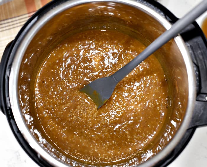 Looking down on pumpkin oatmeal in a pressure cooker, stirred with a gray spatula. 