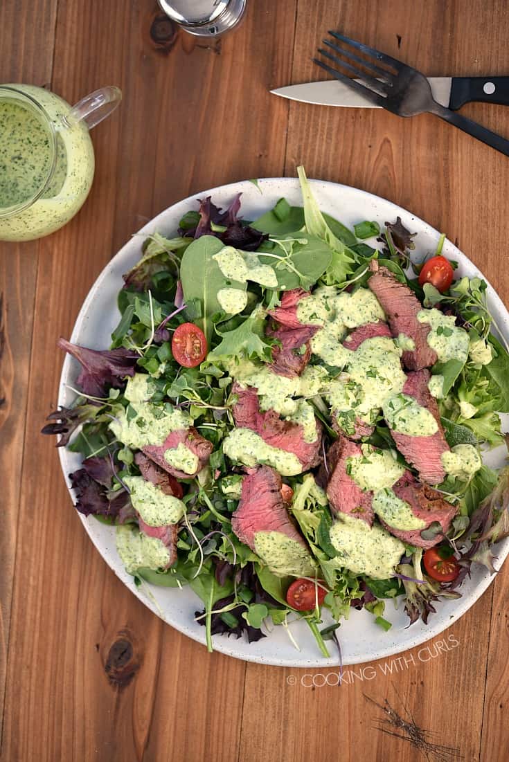Looking down on a Cilantro-Lime Steak Salad, a carafe of cilantro-lime dressing.