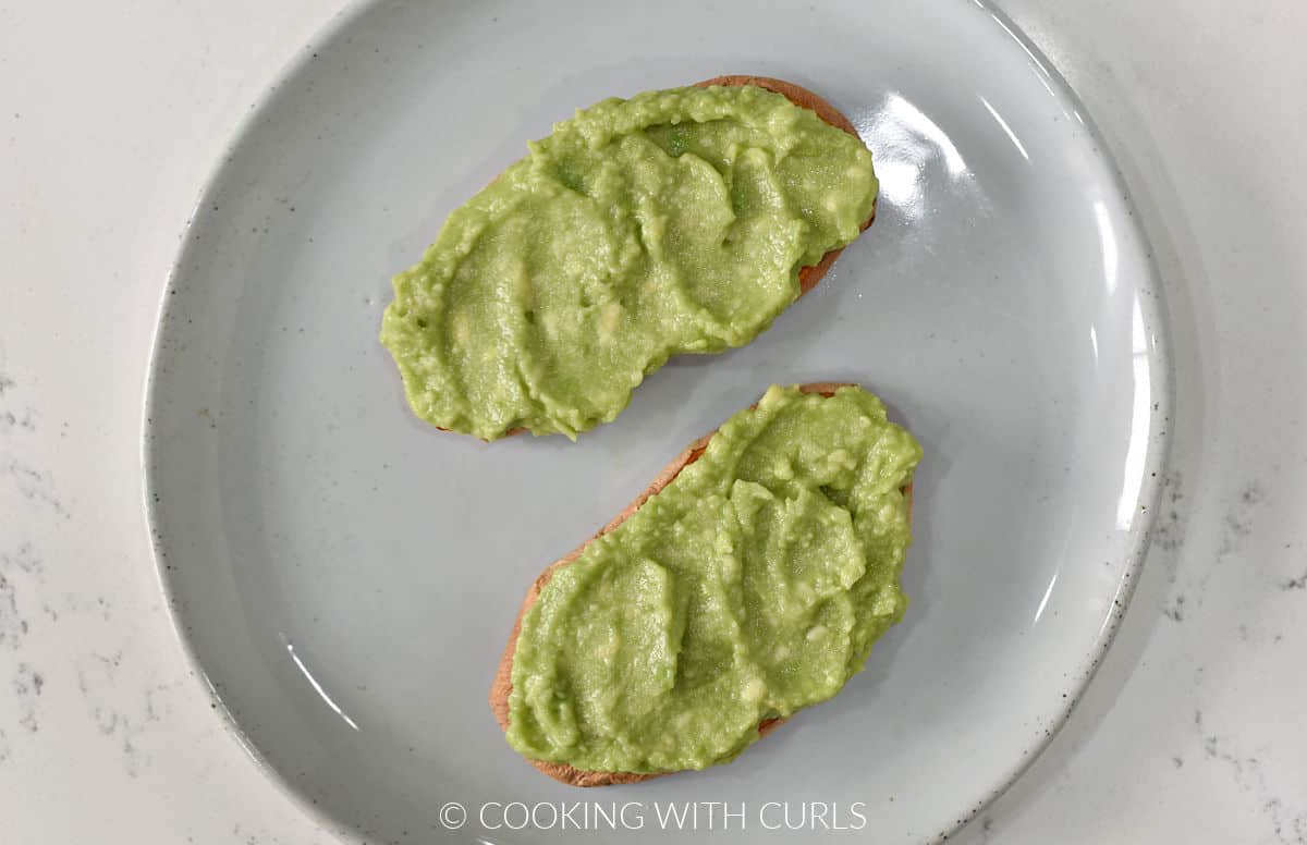 Mashed avocado spread over two slices of sweet potato toast.