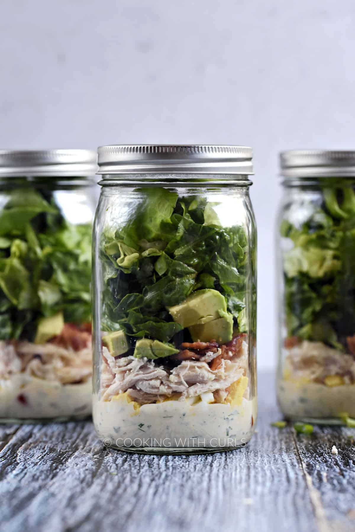 Three Mason Jar Cobb Salad with Ranch Dressing in a row. 