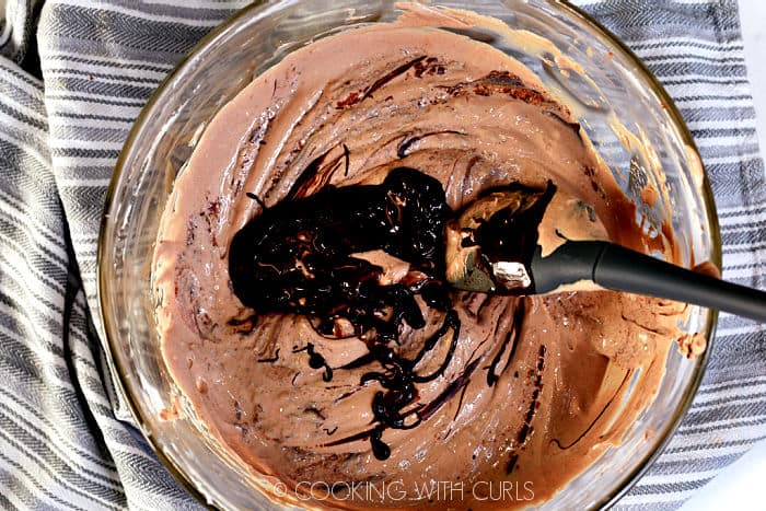 Melted chocolate mixed into the cream cheese mixture with a gray spoonula. 