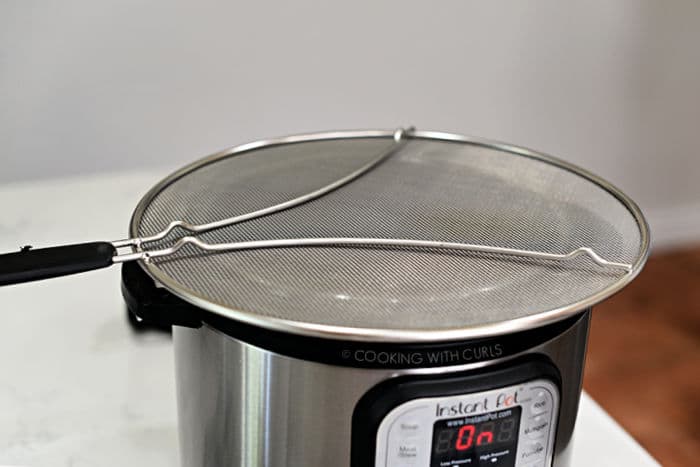 metal splatter screen laying over the top of an open instant pot. 