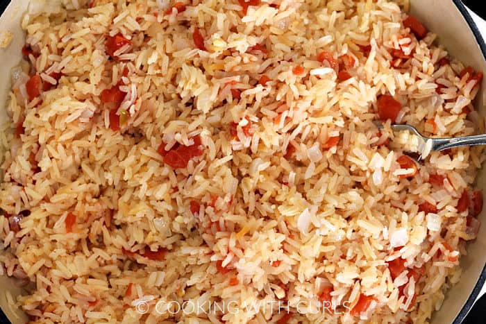 Mexican Rice fluffed with a fork in a large skillet. 