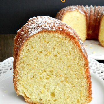 a slice of moroccan orange cake on a decorative white plate with the remaining cake in the background