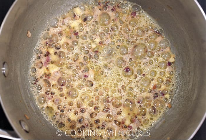 Oil, butter, diced onion, and minced garlic simmering in a saucepan. 