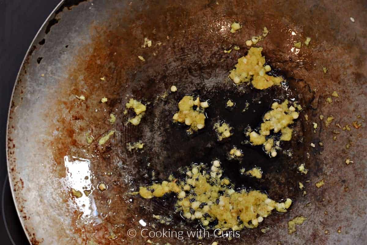 Oil, ginger, and garlic in a wok. 