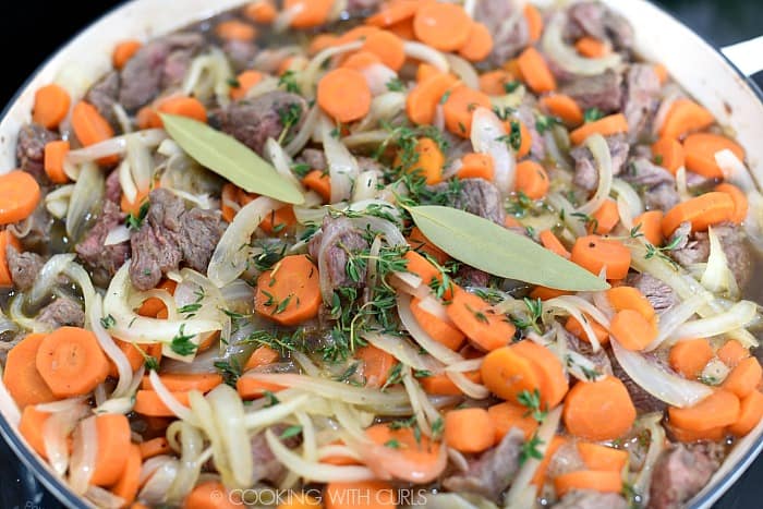 Onion and carrot slices, browned beef chunks, Guinness, thyme and bay leaves in a casserole pan. 