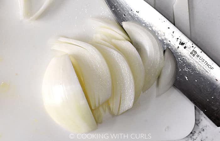 Onion half sliced into thin strips with a chefs knife.