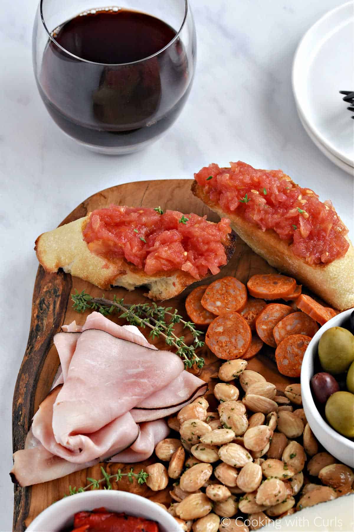 Pan con Tomate on a tapa board with meats and almonds.