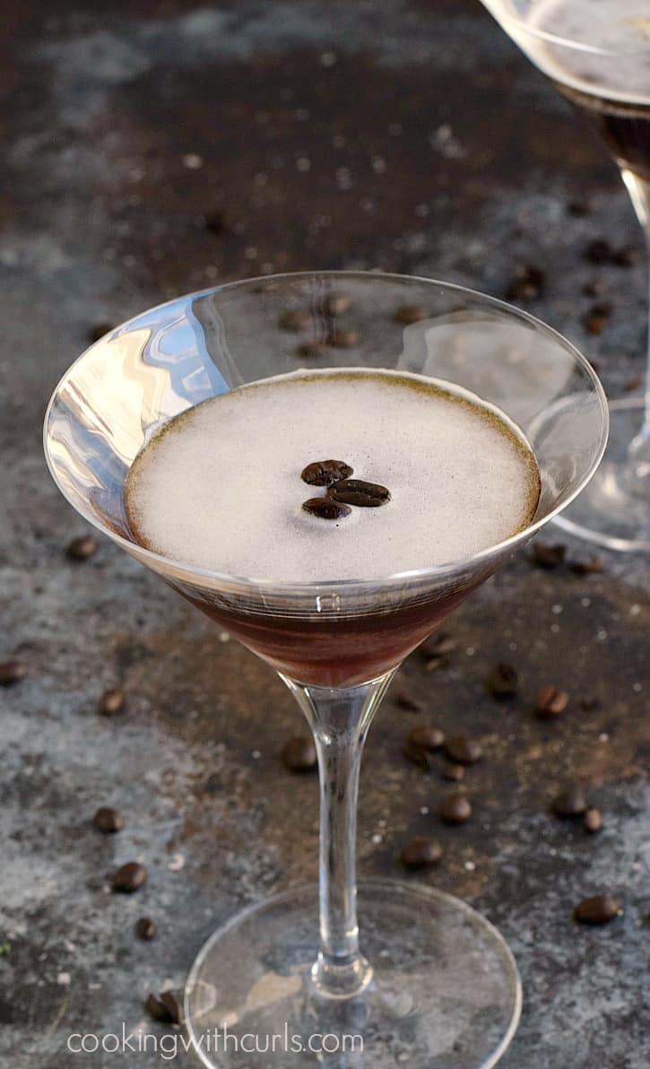 Espresso martini in a martini glass with three coffee beans floating in the center.