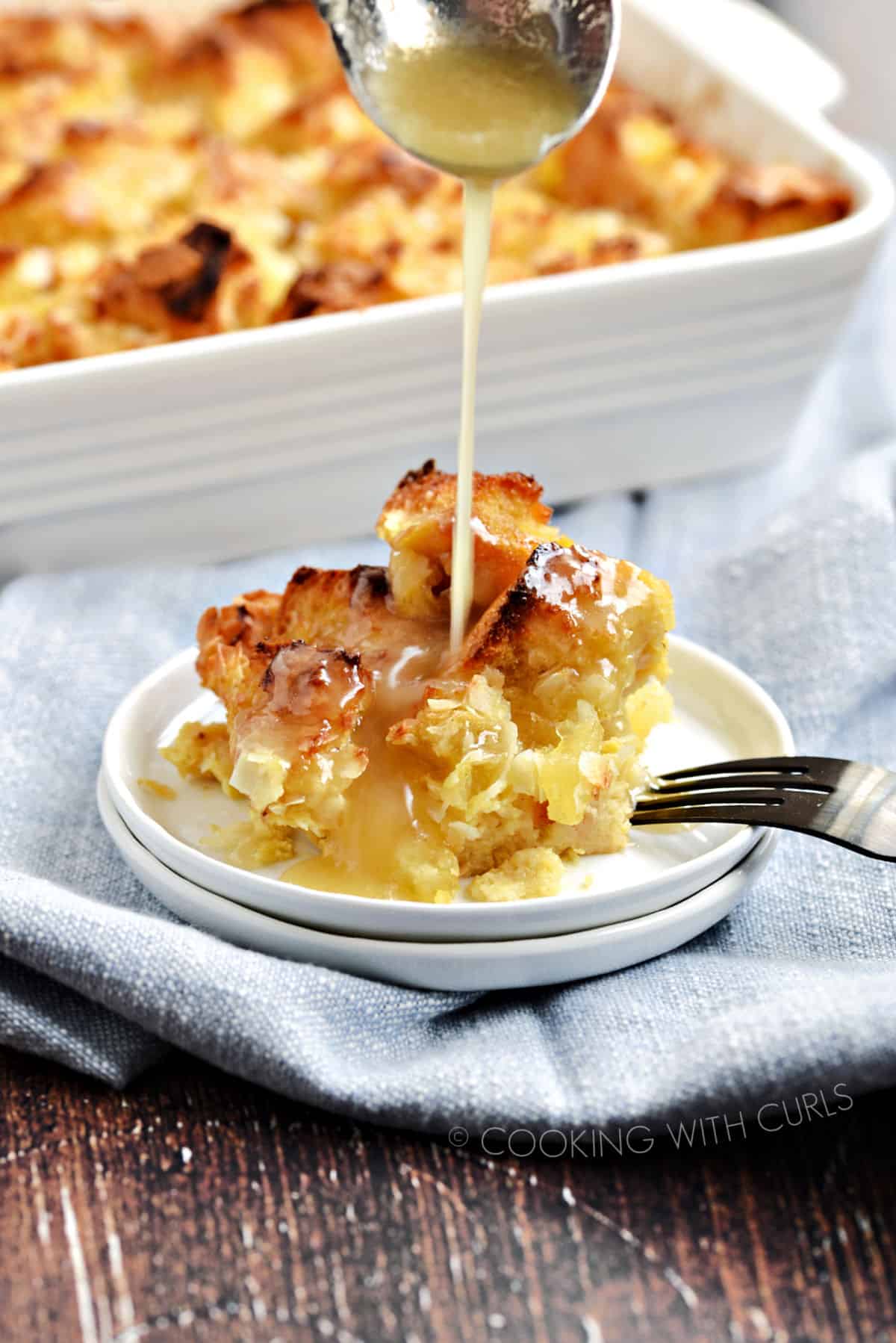 Pina Colada Bread Pudding topped with Coconut Syrup on a small white plate.