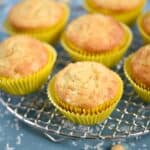 Pina Colada Muffins in yellow wrappers sitting on a wire cooling rack.