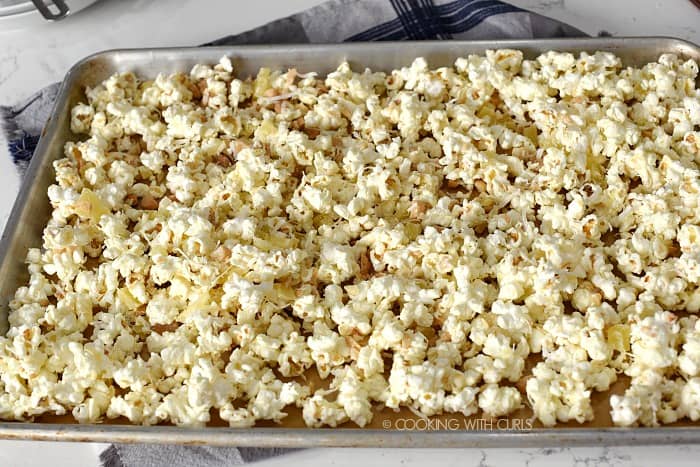 Pina Colada Popcorn spread out over a parchment lined baking sheet 